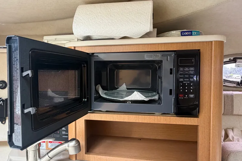 Slide: The Image of Microwave inside 2009 Sea Ray 240 Sundancer boat cabin, with open door and wooden cabinetry. - 64