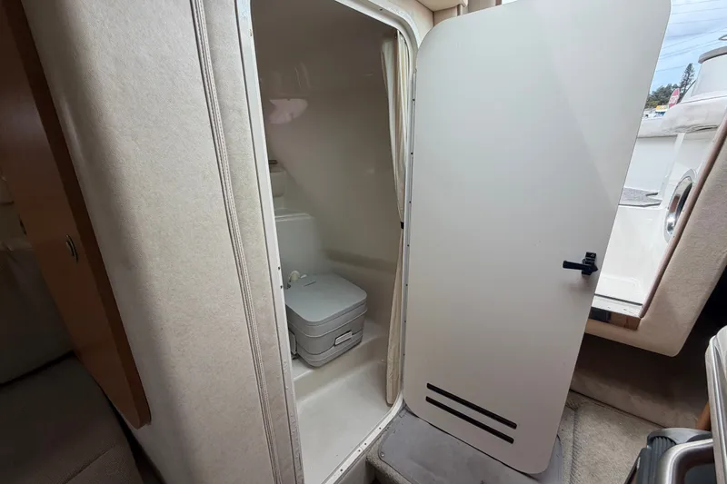 Slide: The Image of 2009 Sea Ray 240 Sundancer cabin bathroom with compact toilet and privacy door. - 79