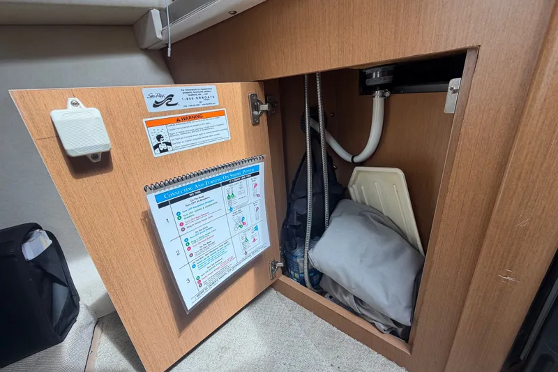 Slide: The Image of Open cabinet in 2009 Sea Ray 240 Sundancer boat showing storage and instructions. - 60