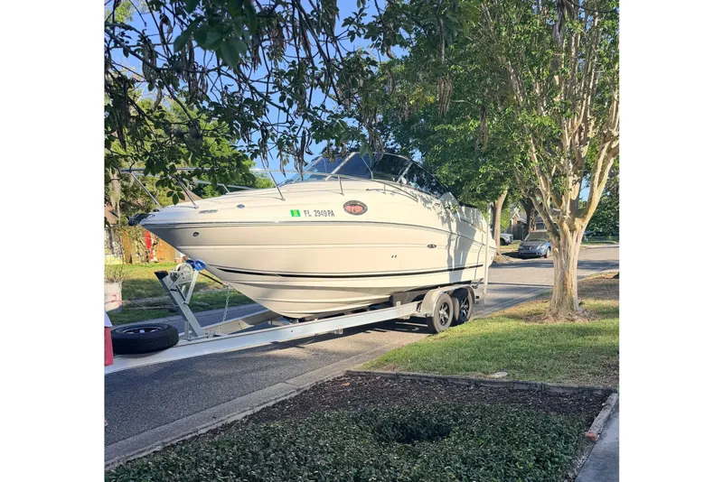 Slide: The Image of A 2009 Sea Ray 240 Sundancer on a trailer in a tree-lined street. - 2