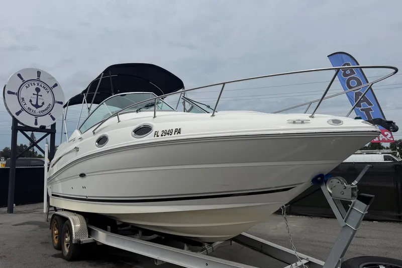 The Image of 2009 Sea Ray 240 Sundancer boat on trailer, displayed at a dealership. - 0