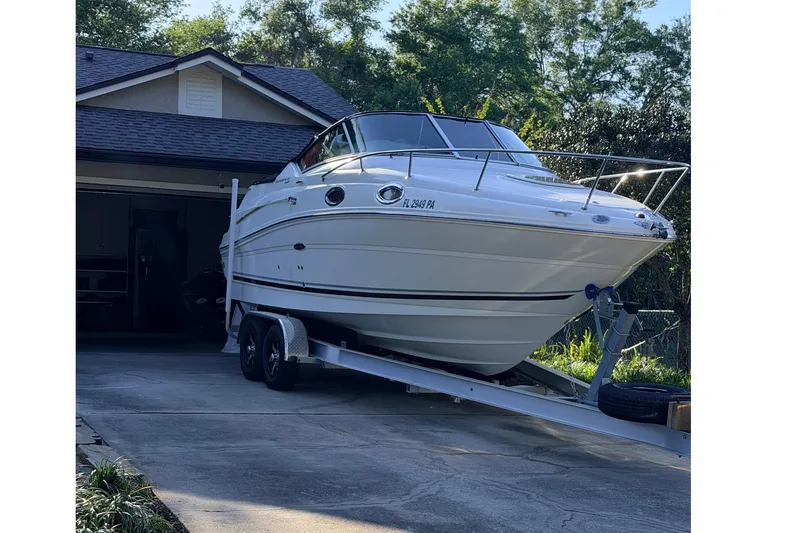 The Image of A white 2009 Sea Ray 240 Sundancer boat on a trailer in front of a garage. - 0