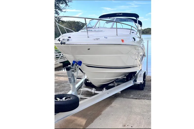 Slide: The Image of A white 2009 Sea Ray 240 Sundancer boat on a trailer by the water. - 1
