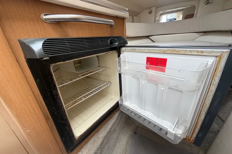 Slide: The Image of Open refrigerator inside 2009 Sea Ray 240 Sundancer boat cabin, showcasing interior shelving. - 68