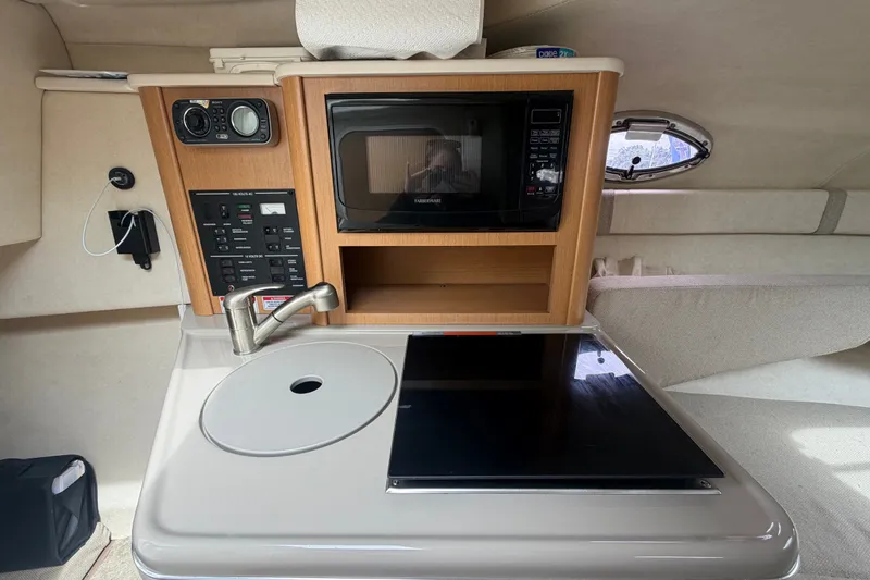 Slide: The Image of 2009 Sea Ray 240 Sundancer cabin with kitchenette, featuring a microwave and sink. - 65