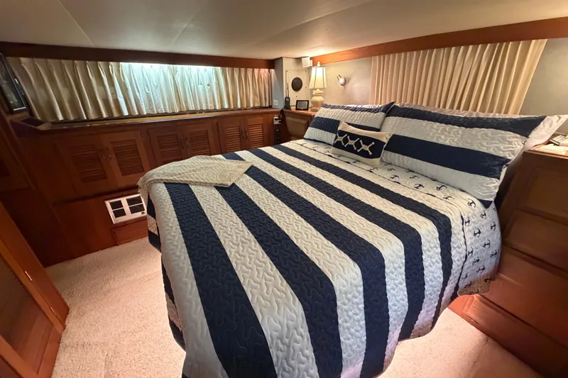 Slide: The Image of Luxurious bedroom interior of 1986 Viking 48 Motor Yacht with striped bedding and wood accents. - 27