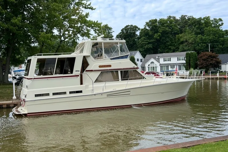 Slide: The Image of 1986 Viking 48 Motor Yacht docked by waterfront homes, surrounded by lush greenery. - 2