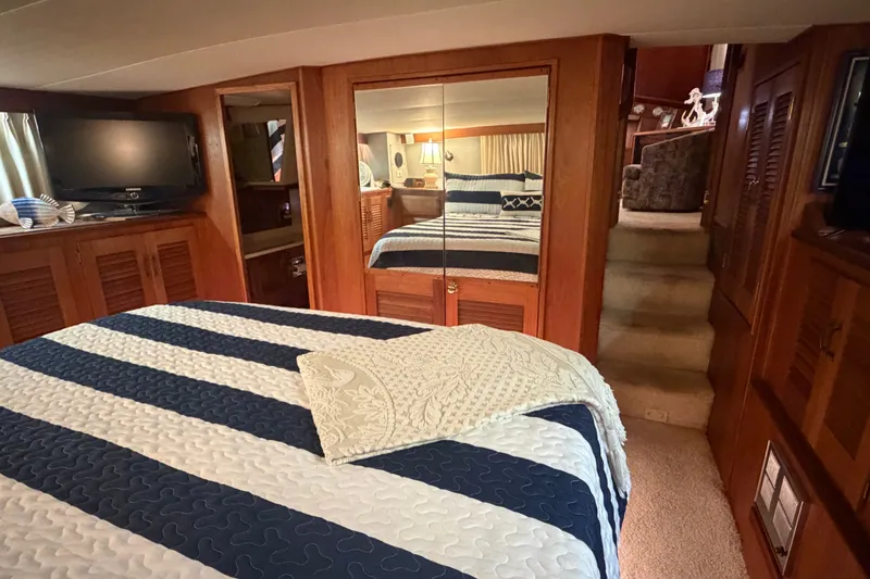 Slide: The Image of Cozy bedroom interior of 1986 Viking 48 Motor Yacht with striped bedding and mirrored closet. - 24