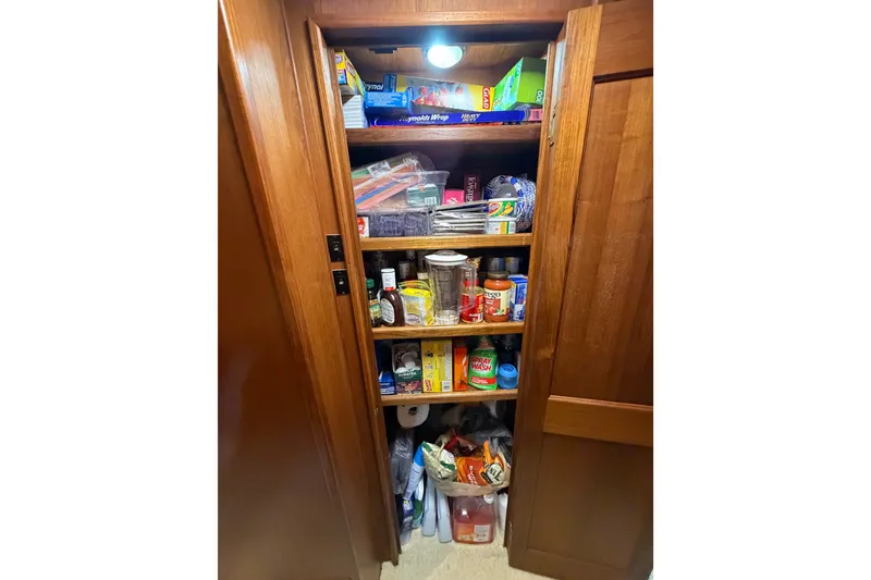 Slide: The Image of Storage pantry inside 1986 Viking 48 Motor Yacht, stocked with various household items and supplies. - 23