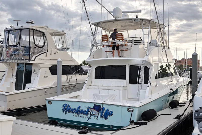 Slide: The Image of 2002 Viking 52 Convertible yacht docked, featuring "Hooked Up" signage and fishing equipment. - 28