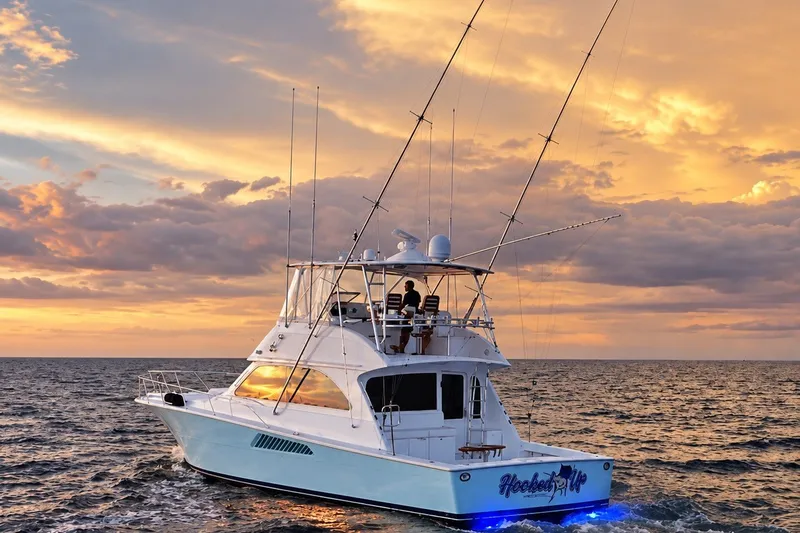 Slide: The Image of 2002 Viking 52 Convertible yacht at sunset on the ocean, with fishing rods and glowing lights. - 23