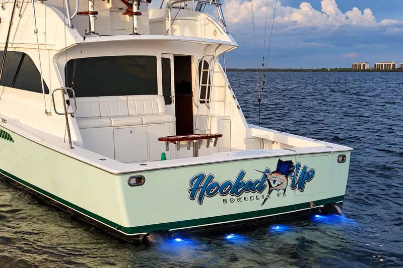 Slide: The Image of 2002 Viking 52 Convertible yacht on water, featuring "Hooked Up" signage and blue underwater lights. - 26