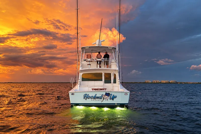 Slide: The Image of 2002 Viking 52 Convertible yacht at sunset with vibrant sky and illuminated water. - 15