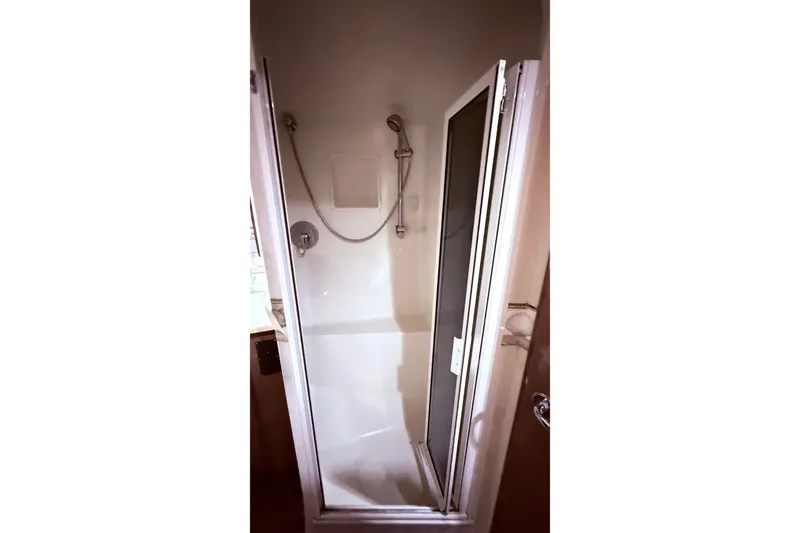 Slide: The Image of Shower area inside a 2002 Viking 52 Convertible yacht, featuring a glass door and handheld showerhead. - 49