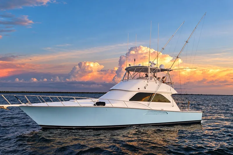 Slide: The Image of 2002 Viking 52 Convertible yacht on water at sunset with vibrant sky. - 25