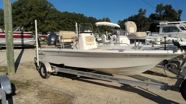 The Image of A white 2016 NauticStar 214 boat on a trailer in a marina area. - 1