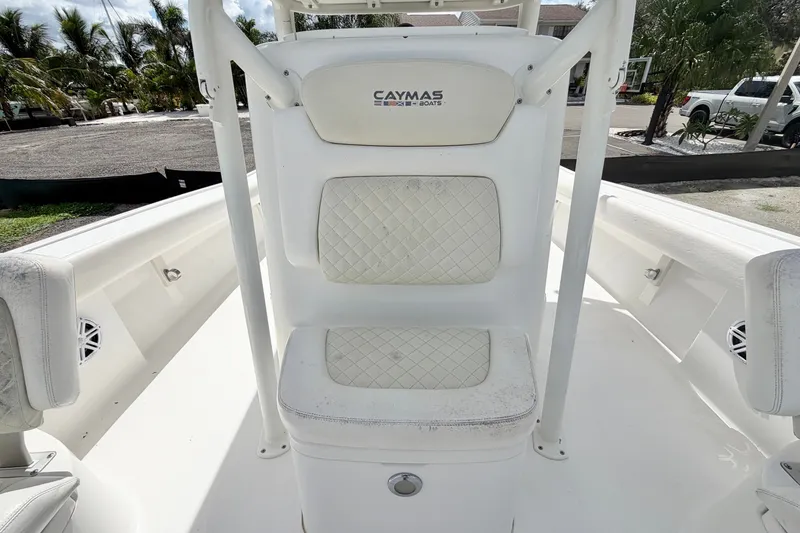 Slide: The Image of 2021 Caymas 28 HB boat interior with white cushioned seating and palm trees in the background. - 21