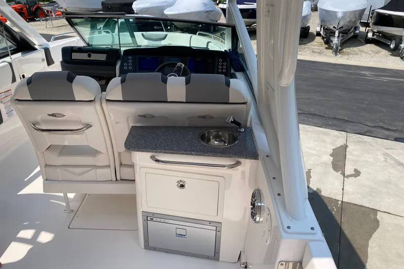 Slide: The Image of 2023 Chaparral 280 OSX boat interior with helm, seating, and compact kitchenette. - 15