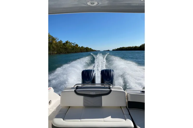 Slide: The Image of 2023 Chaparral 280 OSX boat cruising on a scenic waterway under clear blue skies. - 23