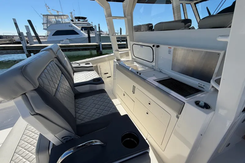 Slide: The Image of 2023 Pursuit S 428 Sport boat interior with seating and grill station at marina. - 16