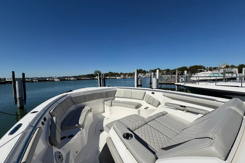 Slide: The Image of 2023 Pursuit S 428 Sport boat with luxurious seating at a marina under clear blue skies. - 24
