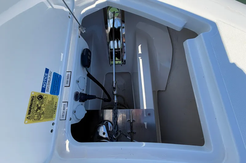 Slide: The Image of 2023 Pursuit S 428 Sport boat anchor compartment with warning labels and water connections. - 30