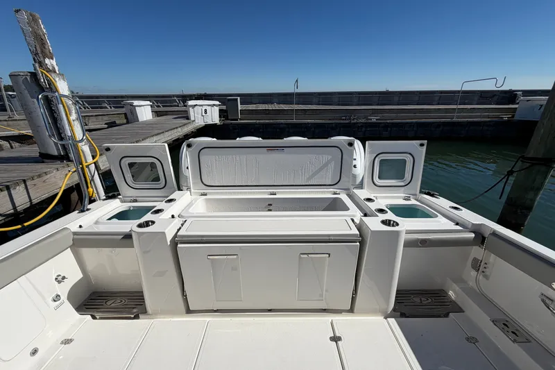Slide: The Image of 2023 Pursuit S 428 Sport boat deck with storage compartments at a marina. - 14