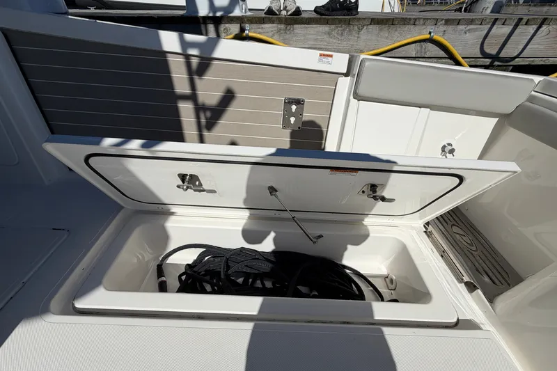 Slide: The Image of Open storage compartment on 2023 Pursuit S 428 Sport boat, containing coiled rope. - 33