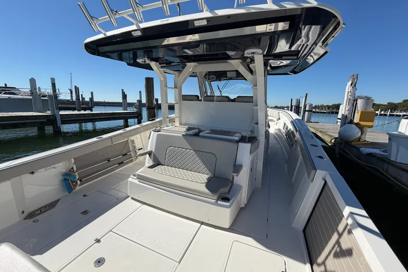Slide: The Image of 2023 Pursuit S 428 Sport boat docked, showcasing spacious deck and seating area. - 12