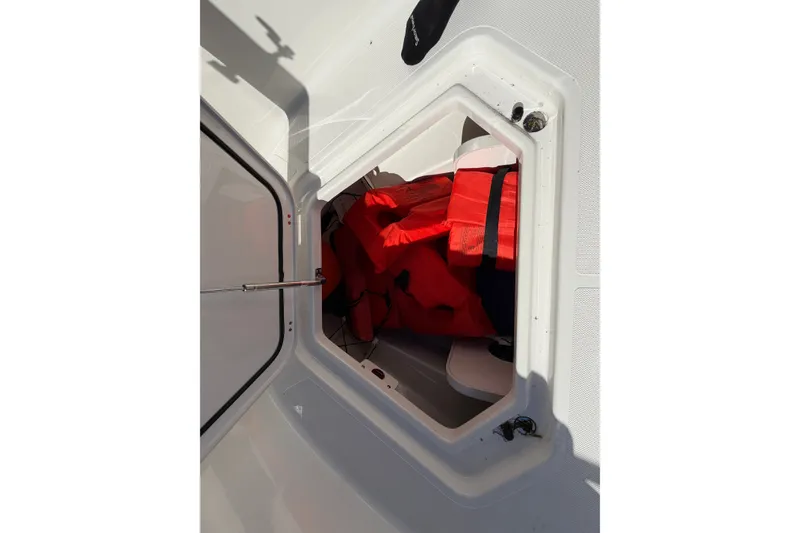 Slide: The Image of Storage compartment with red life jackets on a 2023 Pursuit S 428 Sport boat. - 28