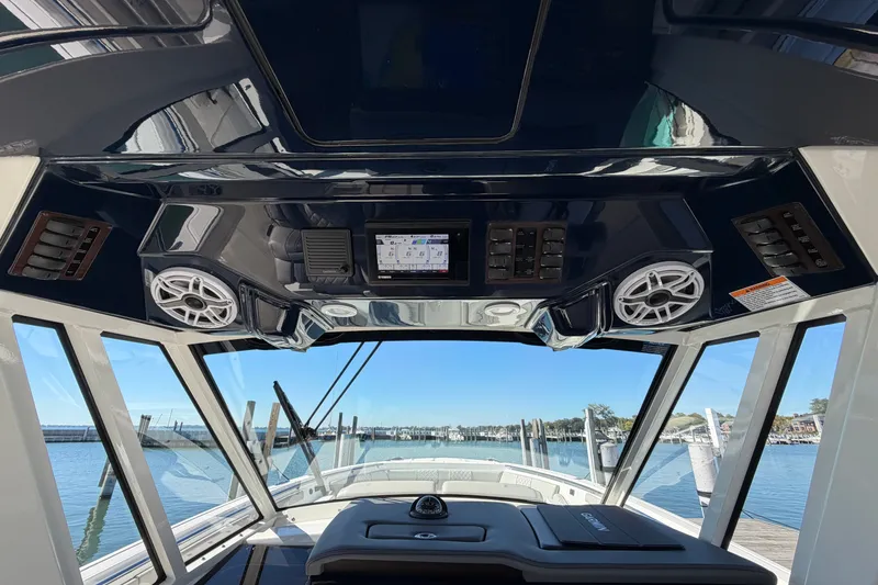 Slide: The Image of 2023 Pursuit S 428 Sport boat interior with advanced dashboard and scenic marina view. - 19