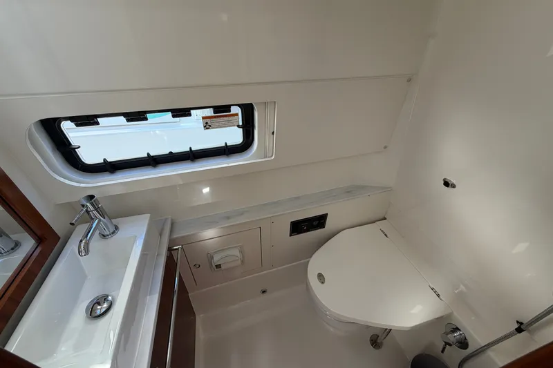Slide: The Image of 2023 Pursuit S 428 Sport boat bathroom with sink, toilet, and window. - 22