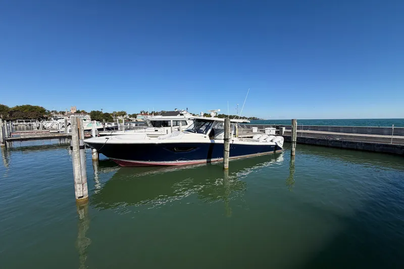 Slide: The Image of 2023 Pursuit S 428 Sport boat docked in a marina under clear blue skies. - 8