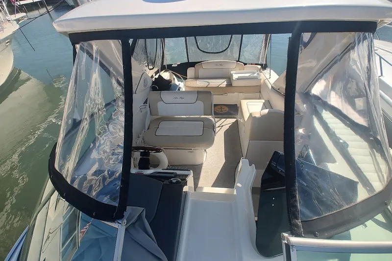 Slide: The Image of 2012 Sea Ray Sundancer 310 interior with seating and clear enclosures, docked on water. - 43