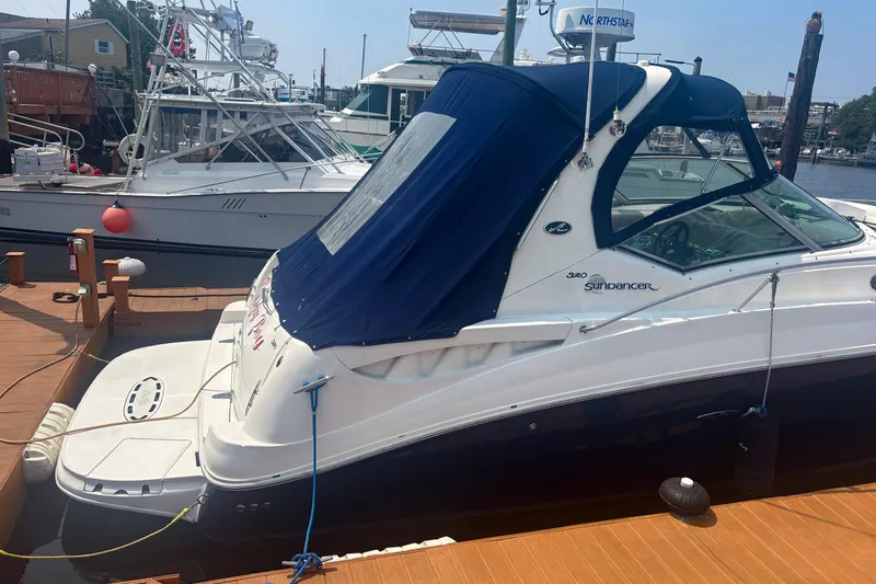 Slide: The Image of 2006 Sea Ray 320 Sundancer docked, featuring a blue canopy and sleek design. - 3
