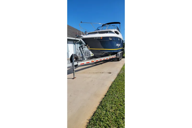 Slide: The Image of 2008 Regal 2565 Express Cruiser on trailer, parked in driveway under clear blue sky. - 6