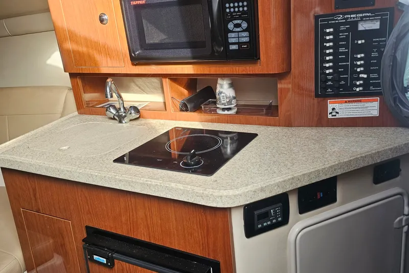 Slide: The Image of 2008 Regal 2565 Express Cruiser interior kitchen with stove, microwave, and control panel. - 2