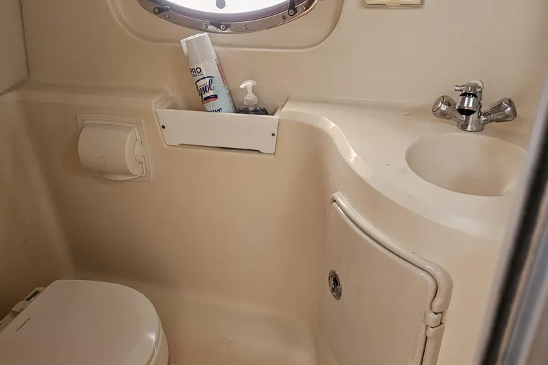 Slide: The Image of 2008 Regal 2565 Express Cruiser bathroom with sink, toilet, and cleaning supplies. - 4
