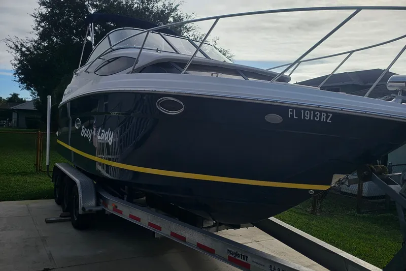The Image of 2008 Regal 2565 Express Cruiser on trailer, parked outdoors, showcasing sleek design and registration number. - 0