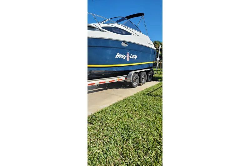 Slide: The Image of 2008 Regal 2565 Express Cruiser on trailer, blue hull, parked on grass. - 7