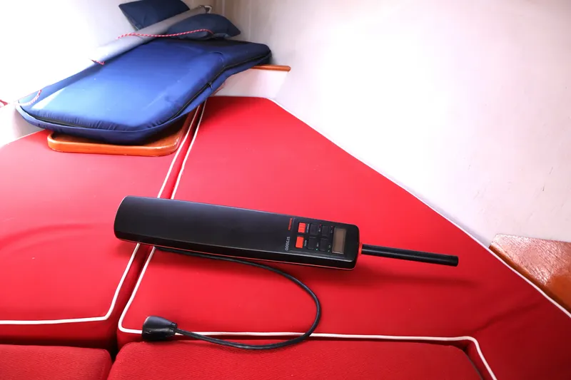 Slide: The Image of Interior of 1995 Alerion Express 28 sailboat with red cushions and a handheld device. - 28