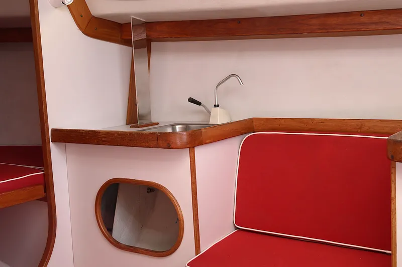Slide: The Image of Interior of 1995 Alerion Express 28 sailboat with red seating and compact kitchenette. - 34