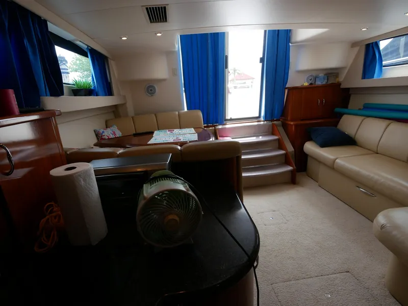 Slide: The Image of Der Innenraum einer Carver 360 Mariner von 2005 mit beigen Sofas und blauen Vorhängen. - 44