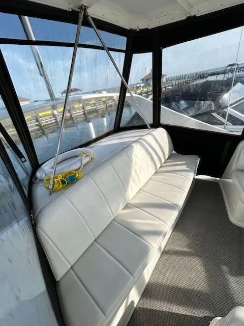Slide: The Image of Die Carver 360 Mariner von 2005 zeigt eine geräumige, gepolsterte Sitzbank im Innenbereich mit großen Fenstern. - 16
