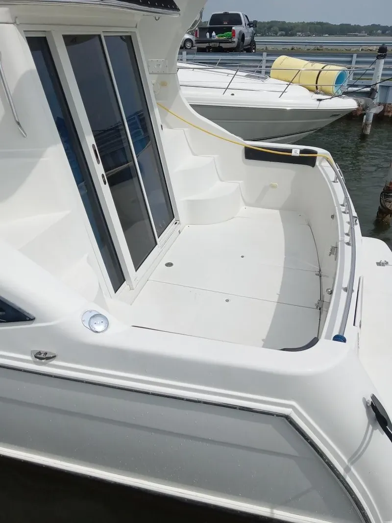 Slide: The Image of Die Carver 360 Mariner von 2005 zeigt ein geräumiges Achterdeck mit Zugangstüren und umliegendem Wasser. - 7