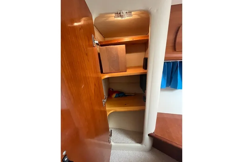 Slide: The Image of Open wooden cabinet inside 2005 Carver 360 Mariner boat, showcasing storage shelves. - 53