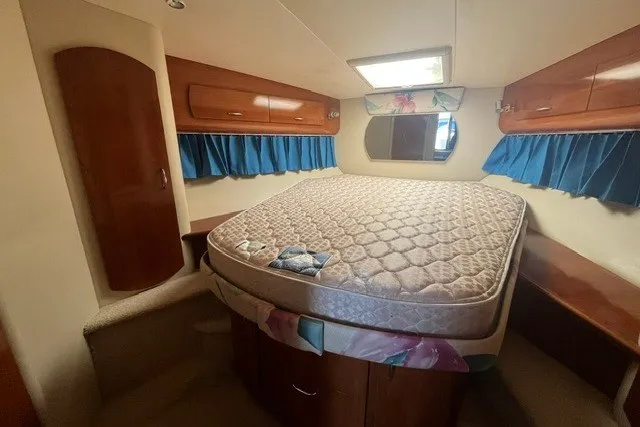 Slide: The Image of Interior cabin of 2005 Carver 360 Mariner with bed, wooden cabinets, and blue curtains. - 50