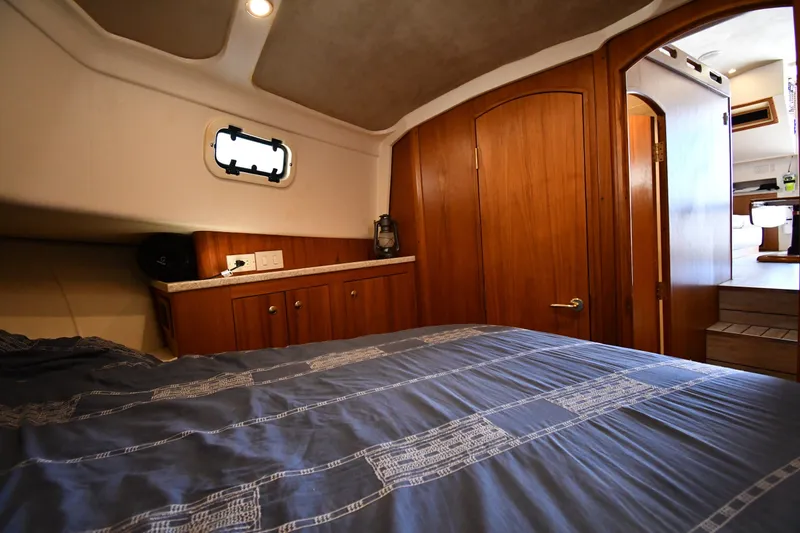 Slide: The Image of Cozy cabin interior of 2000 Mainship 390 Trawler with wooden cabinetry and bed. - 30