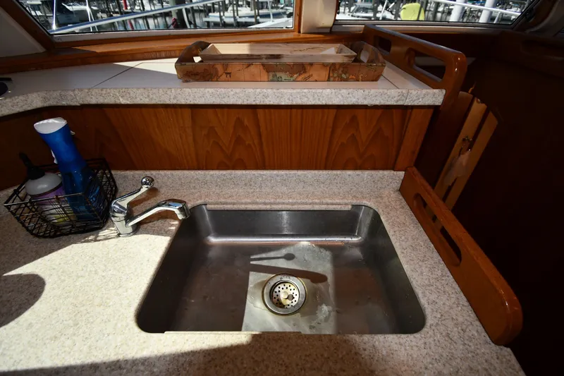 Slide: The Image of 2000 Mainship 390 Trawler kitchen sink with countertop and cleaning supplies. - 41