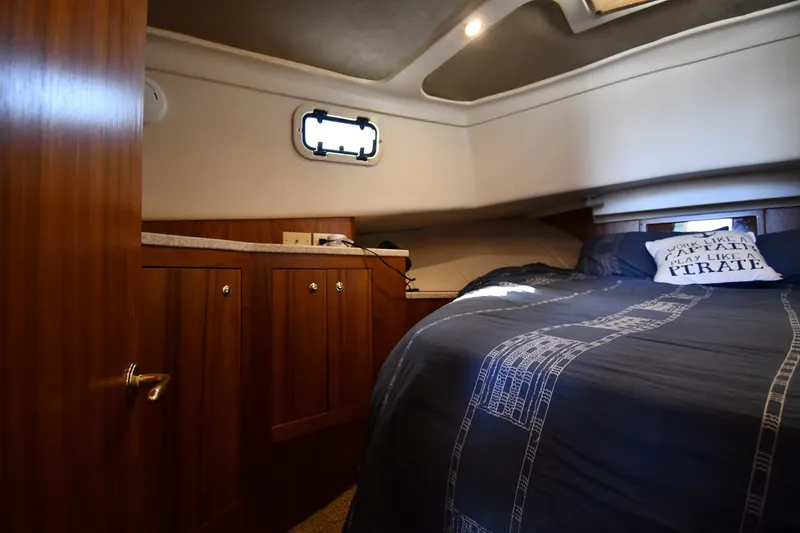 Slide: The Image of Cozy cabin interior of 2000 Mainship 390 Trawler with wooden cabinets and nautical bedding. - 28
